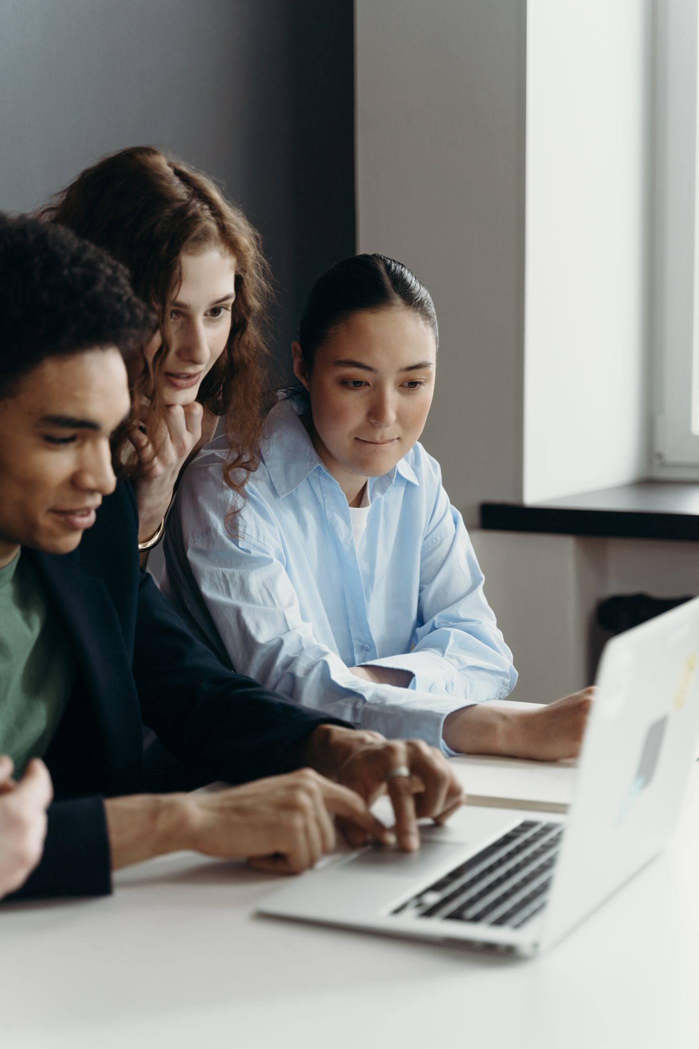 A workplace team collaborating around a laptop